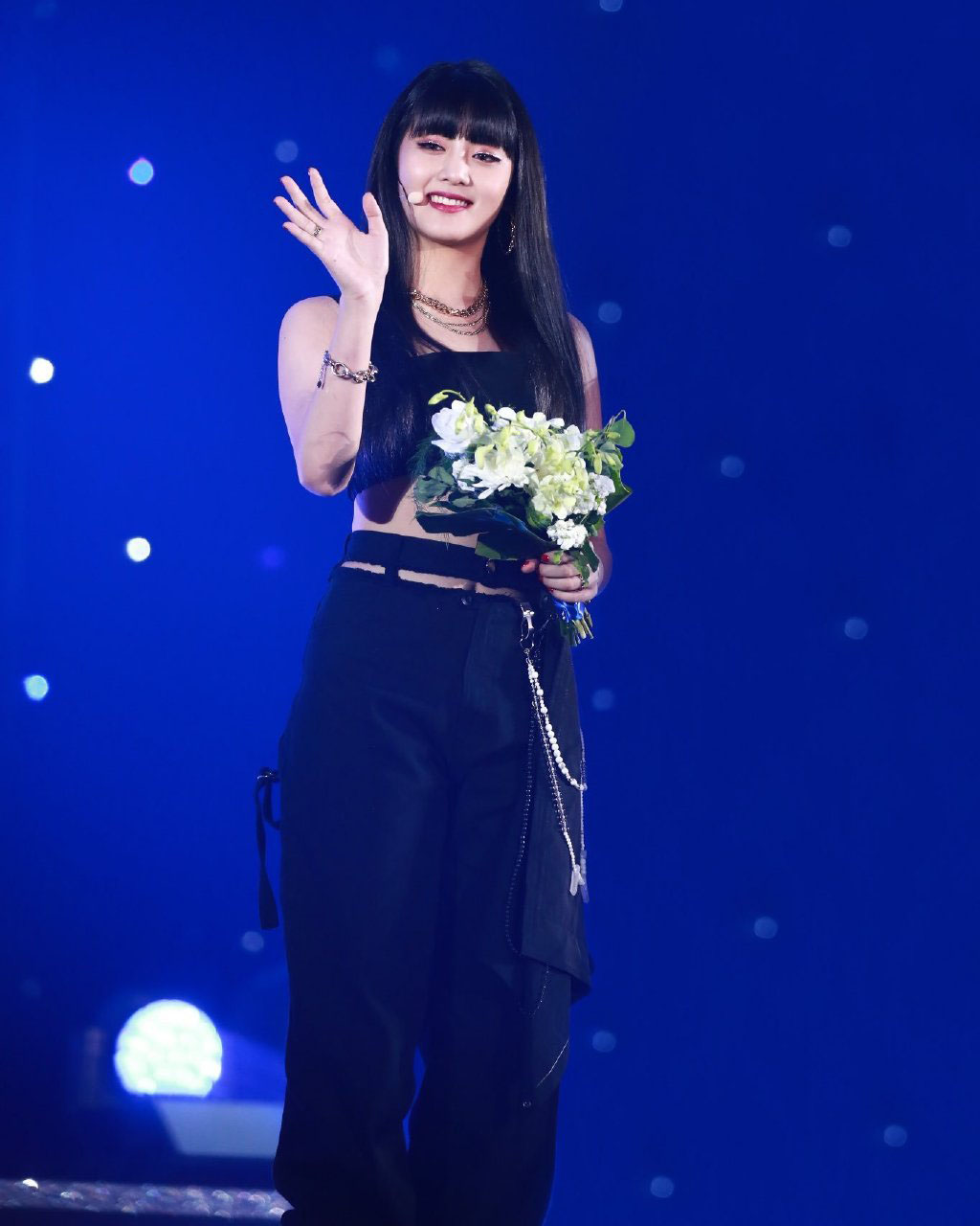 她是组合梦幻主唱，穿白底黑线休闲套装，发带增加运动感