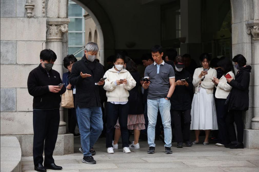 韩国人低头看智能手机，手指疯狂地敲击屏幕，这是最新的赚钱趋势